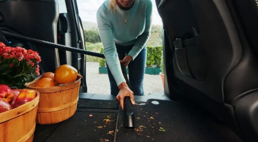 A person is shown vacuuming debris in a 2023 Chrysler Pacifica.