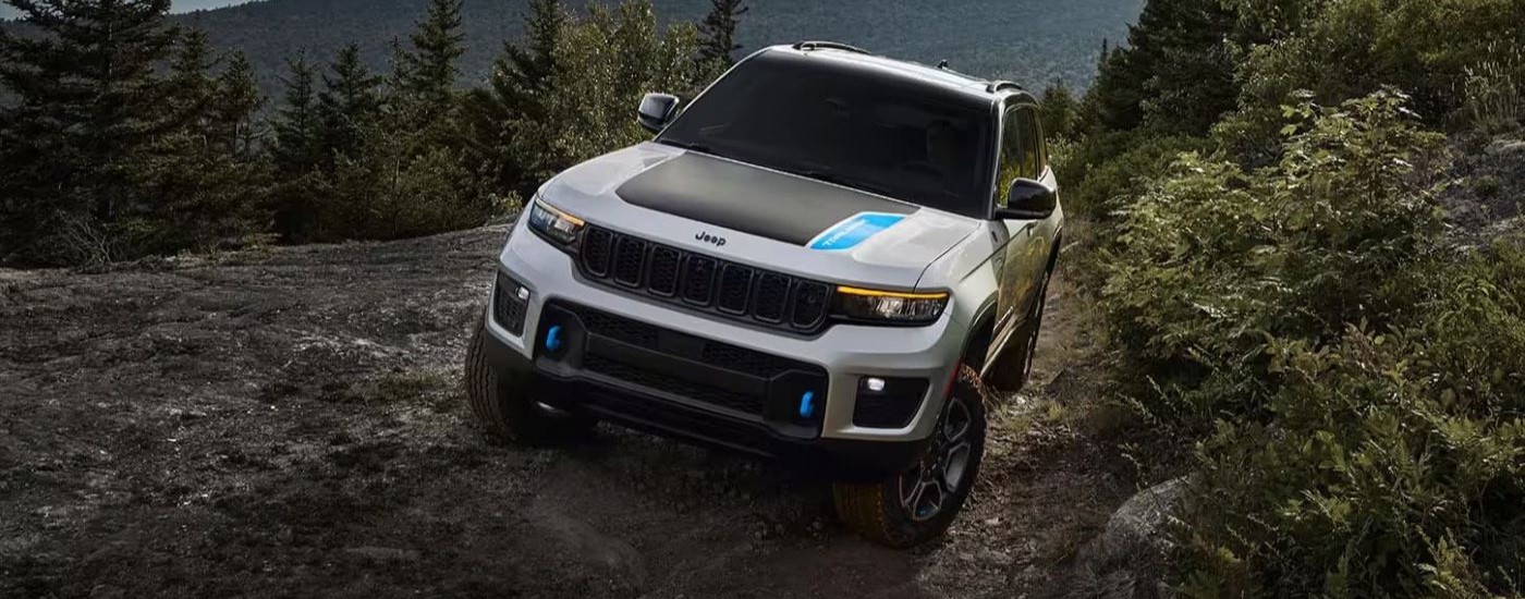 A silver 2023 Grand Cherokee 4xe is shown off-roading.