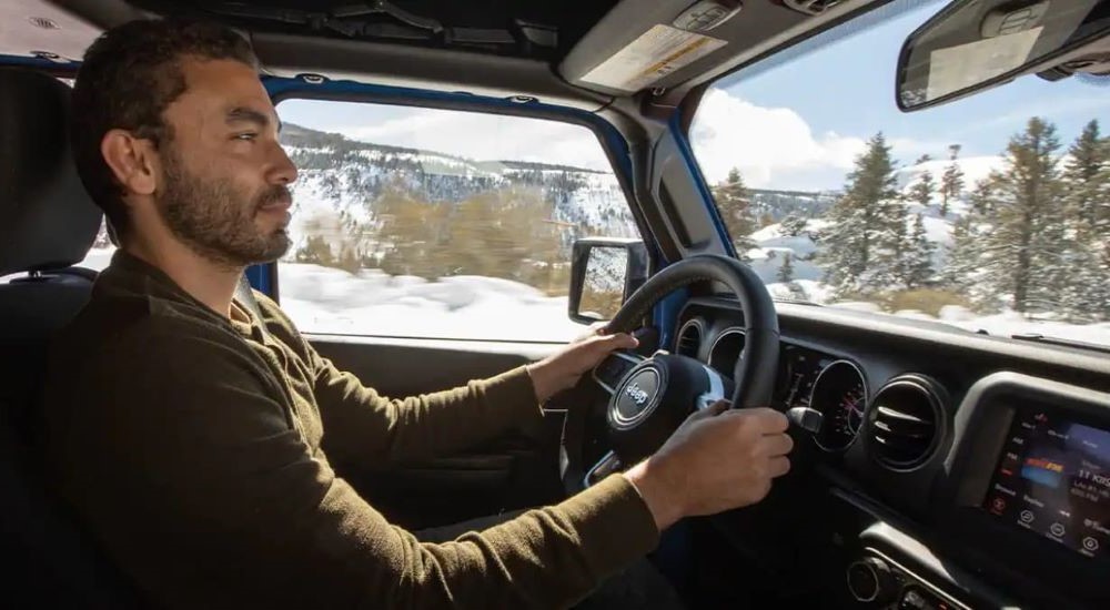A close up shows a person driving a 2023 Jeep Gladiator.
