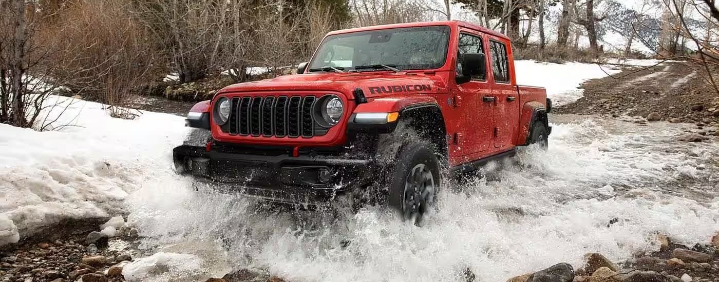 A red 2023 Jeep Gladiator is shown off-road after leaving a Jeep dealer.