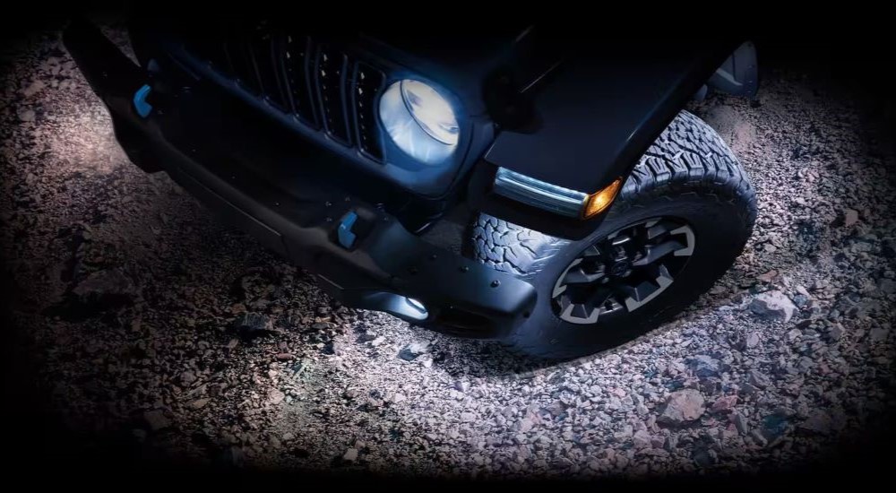 A close up shows the front end of a black 2024 Jeep Wrangler 4xe.