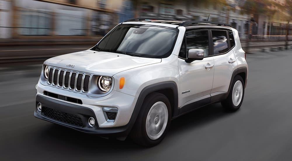 A white 2020 Jeep Renegade is shown from the side on a city street.