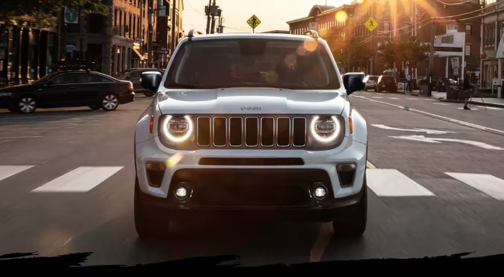 A white 2022 Jeep Renegade is shown driving through a city intersection.