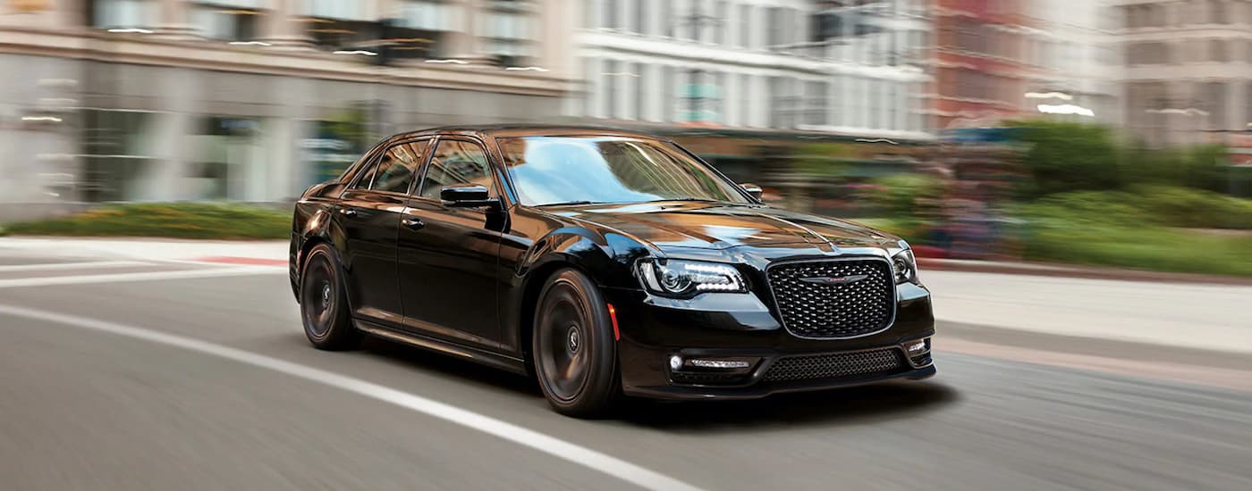 A black 2022 Chrysler 300 is shown driving on a city street after leaving a used Chrysler dealer.