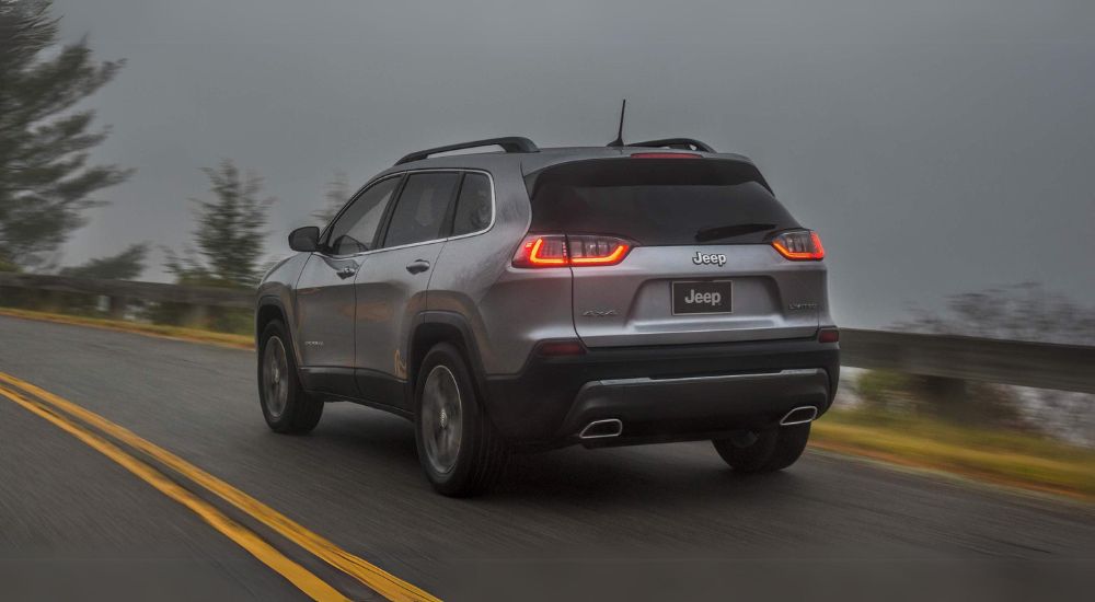 A grey 2022 Jeep Cherokee Limited is shown from the rear driving on a foggy day.