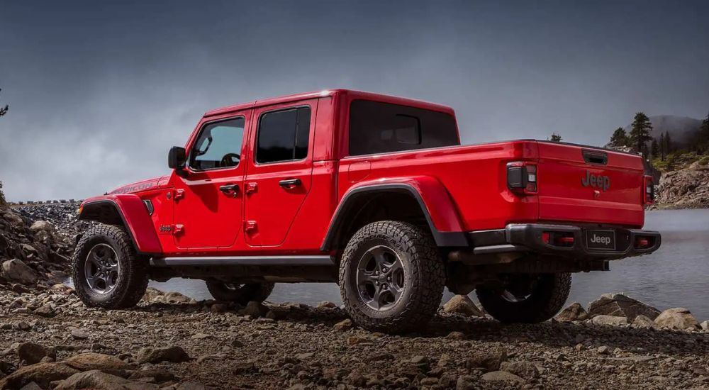 A red 2023 Jeep Gladiator Rubicon is shown parked near a lake.