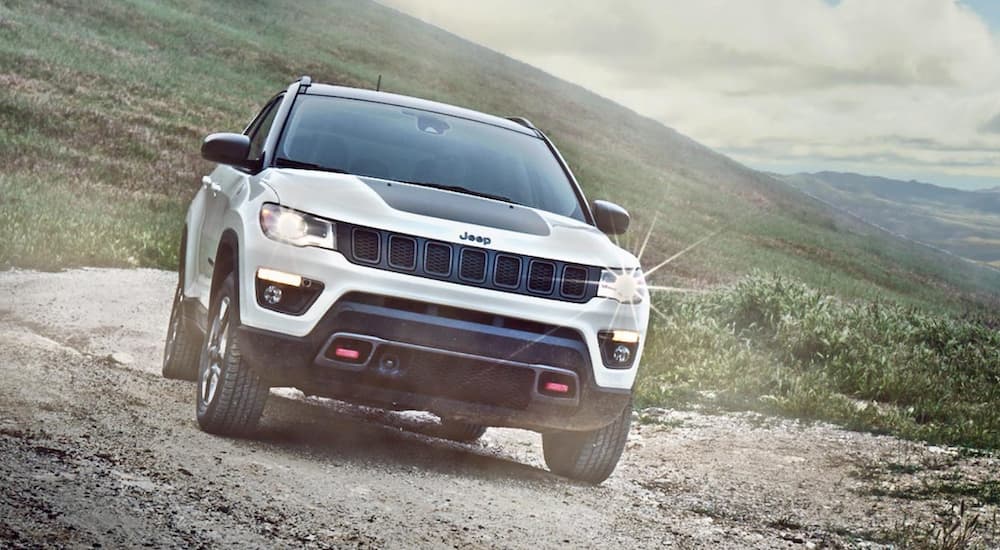 A white 2020 Jeep Compass Trailhawk is shown off-roading after leaving a used Jeep dealer.