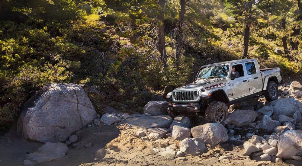 A silver 2024 Jeep Gladiator Rubicon is shown off-roading after leaving a Jeep dealer near Rockland.